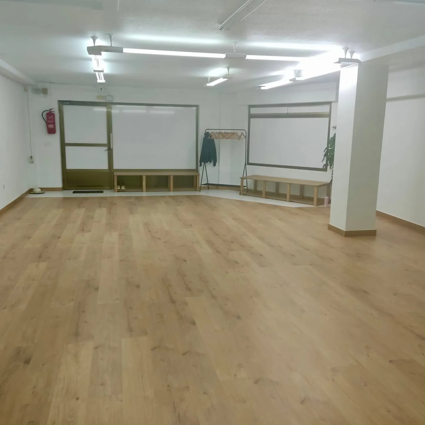 Sala diáfana con suelo de madera y zona de entrada con banco