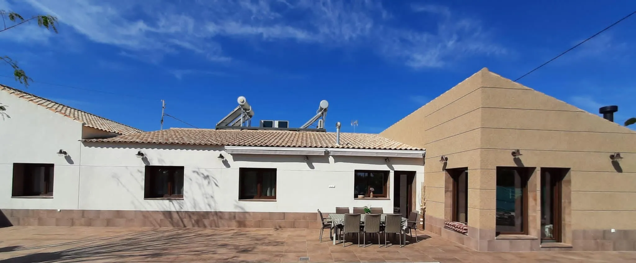 Vista panorámica del patio con la vivienda de una planta y el volumen de la entrada
