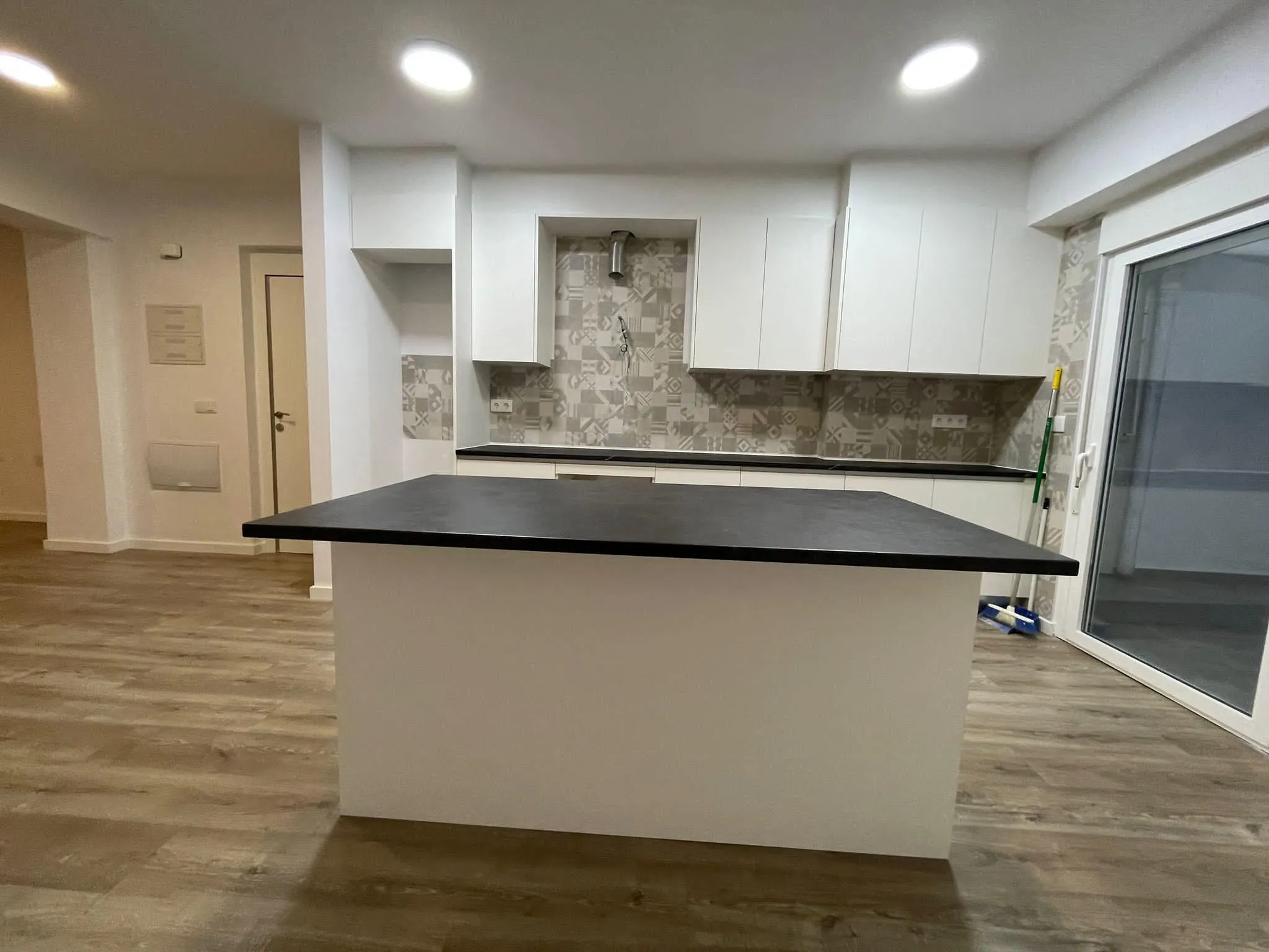 Cocina con isla y encimera negra, vista desde el salón
